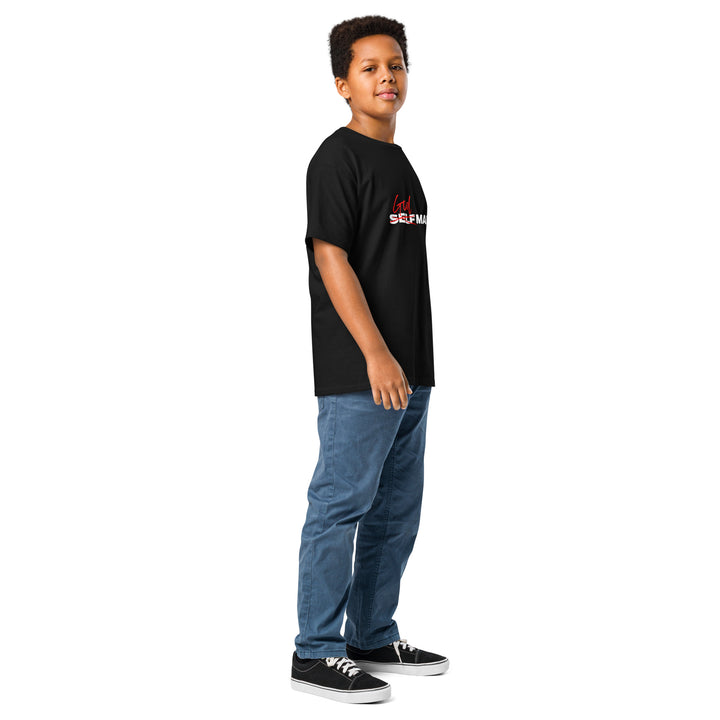 Child wearing a black God Made  t-shirt with red and white text and blue jeans on a white background