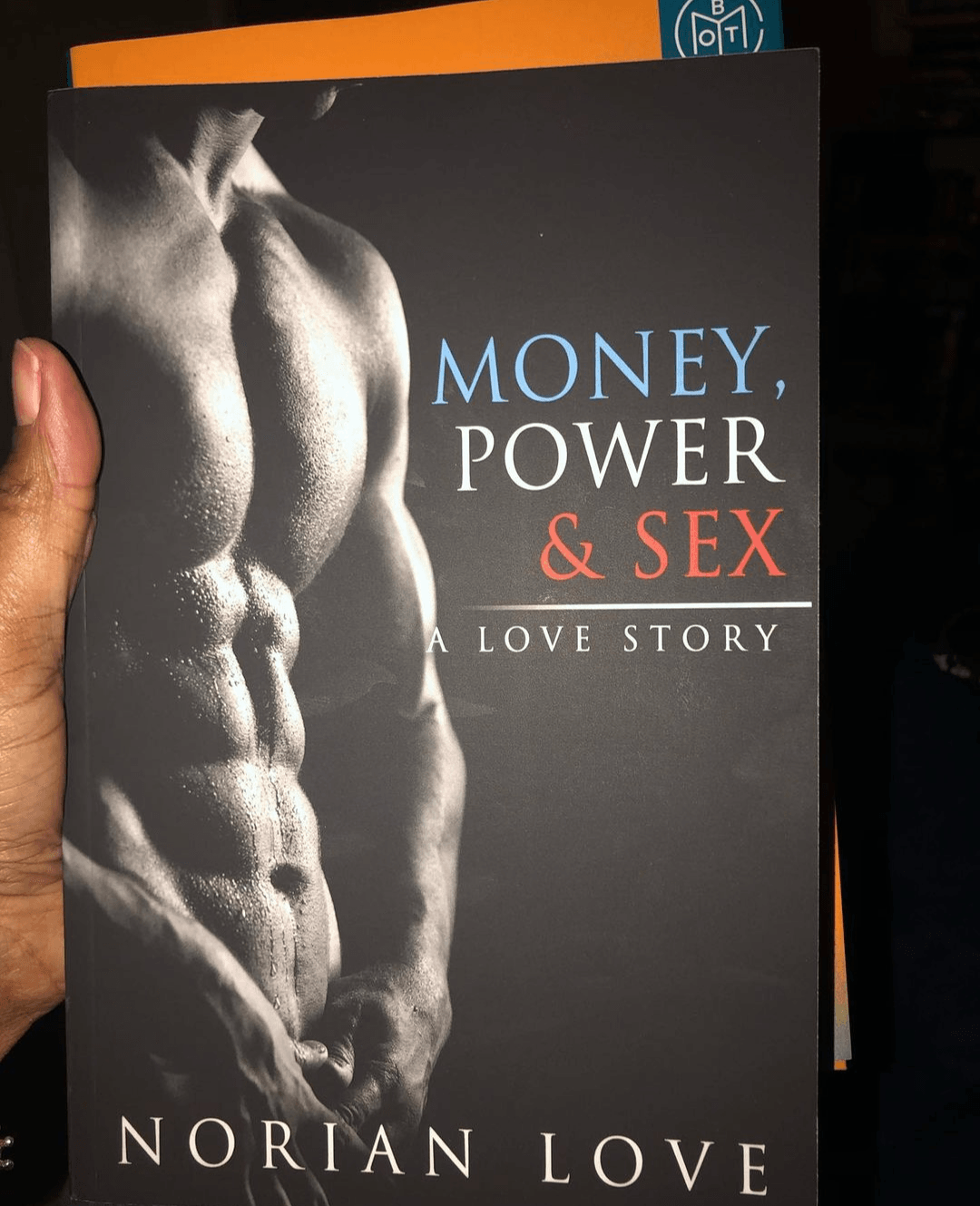 person holding a copy of Money Power, & Sex: A Love Story by  Norian Love