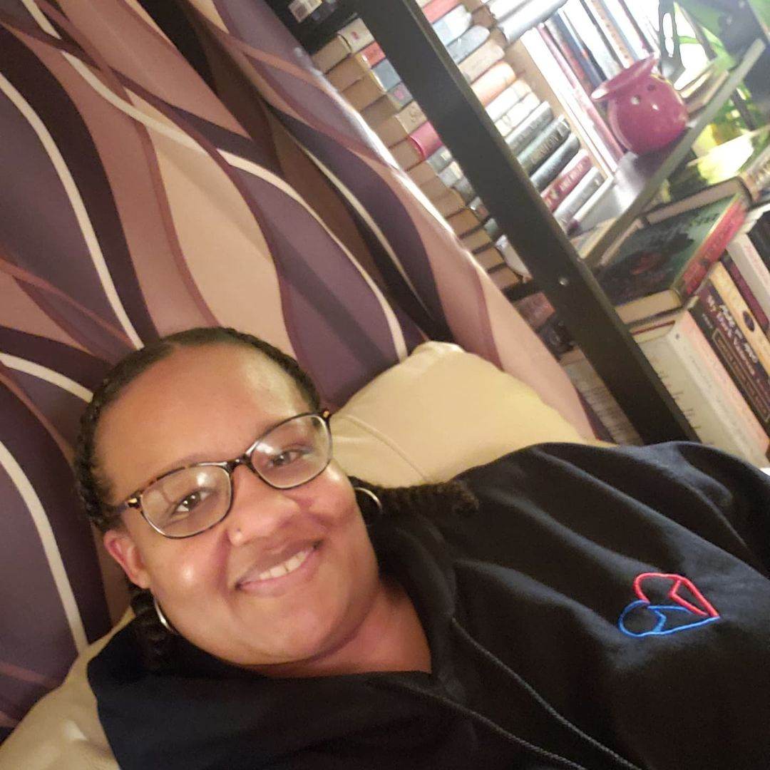 Woman in glasses wearing the Love Clan Classic Embroidered Hoodie by Norian Love