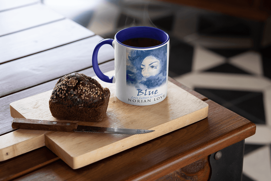 Blue Love mug with blue interior placed on a cutting board beside a seeded muffin.