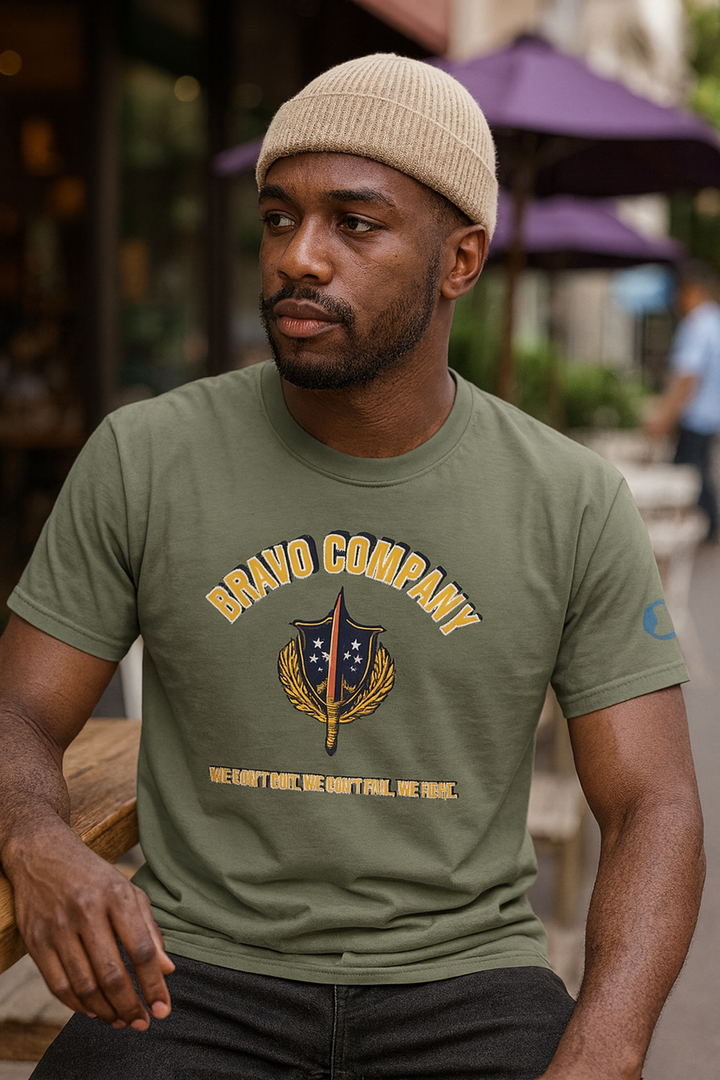 Black man wearing a military green Bravo Company shirt sitting outside a café