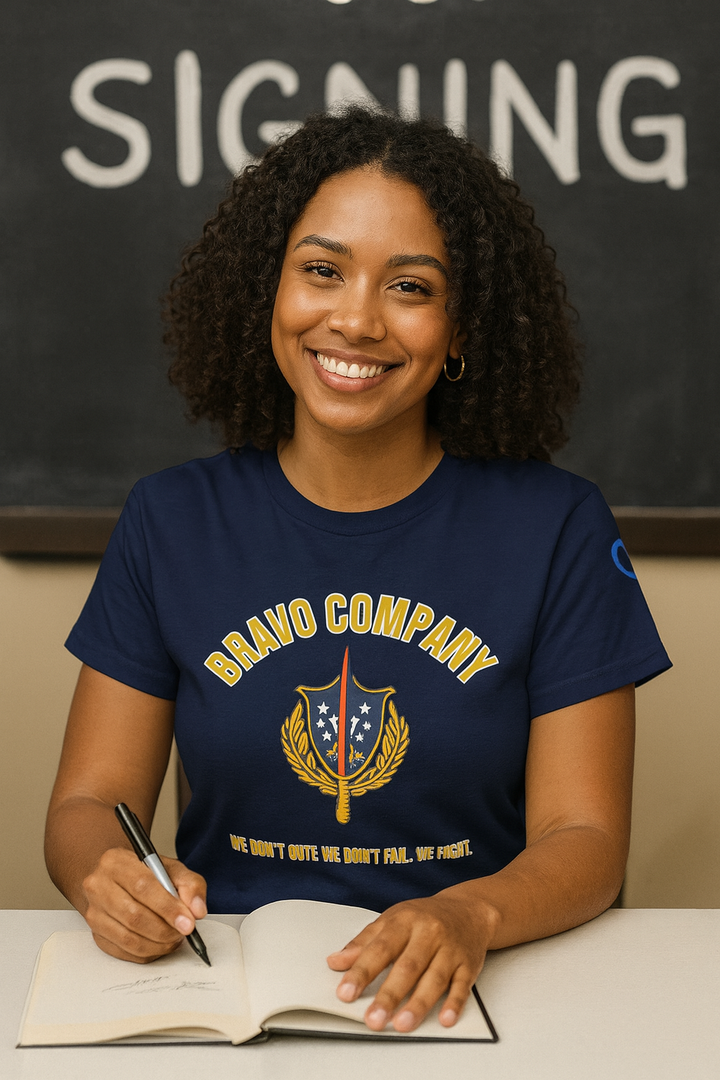 Person wearing a navy blue t-shirt with 'Bravo Company' design, sitting at a desk with a notebook and pen.