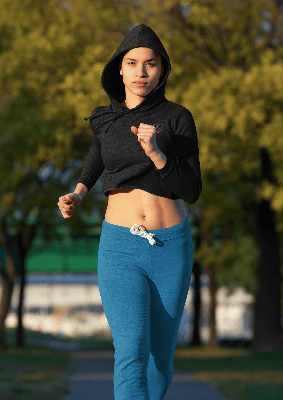 Woman running in a Love Clan black cropped hoodie styled with blue joggers