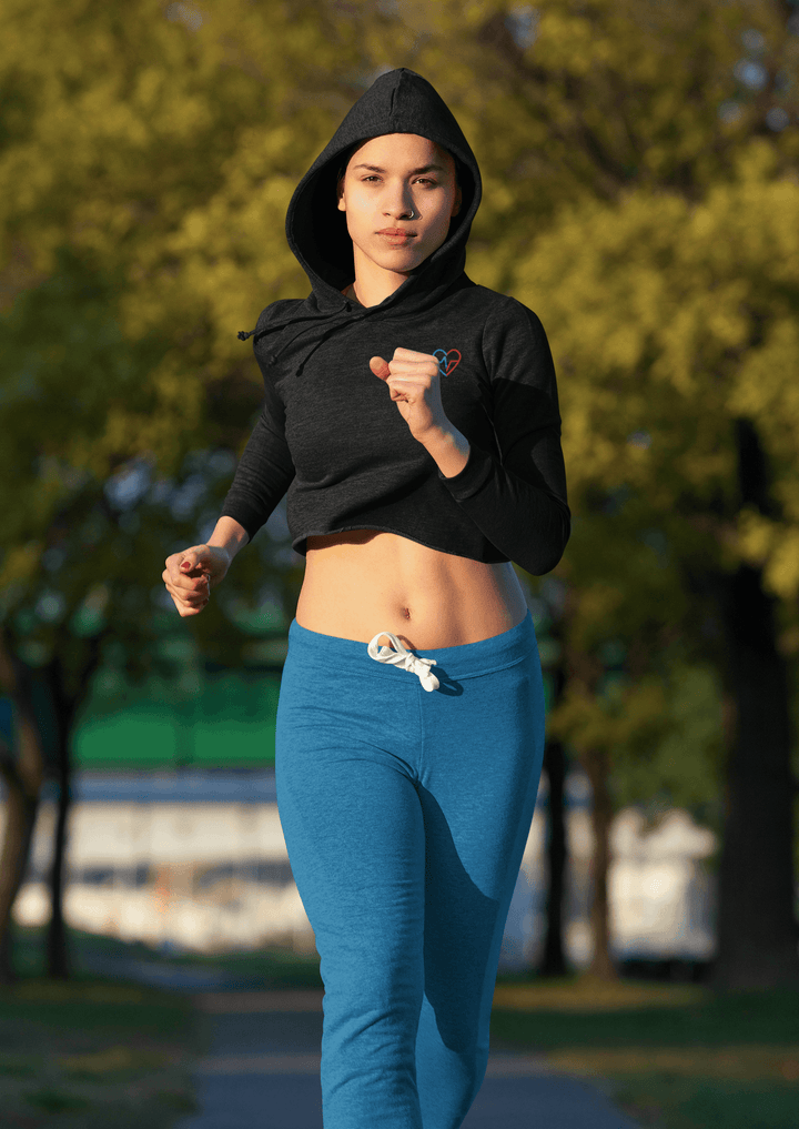 Woman running in a Love Clan black cropped hoodie styled with blue joggers