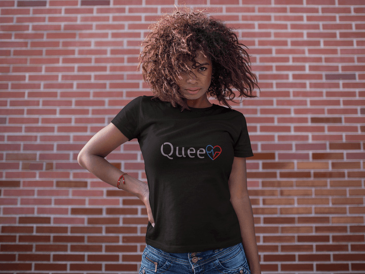 Black woman in front of a brick wall wearing the Love Is Queen empowerment shirt.