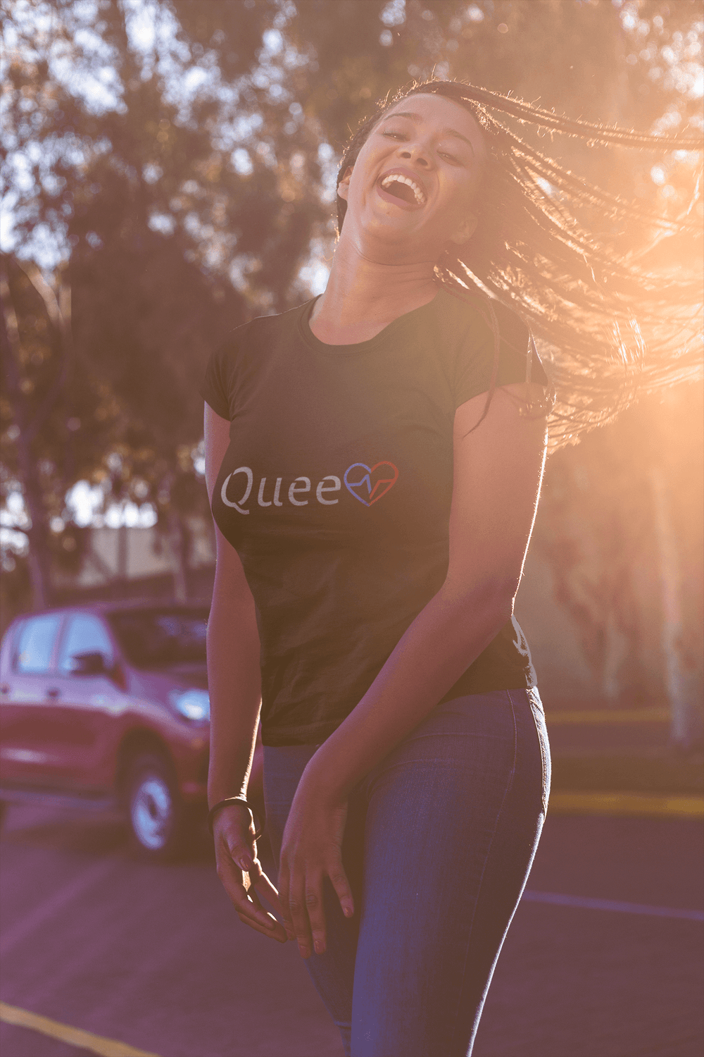 Black woman laughing in sunlight while wearing the Love Is Queen graphic tee.